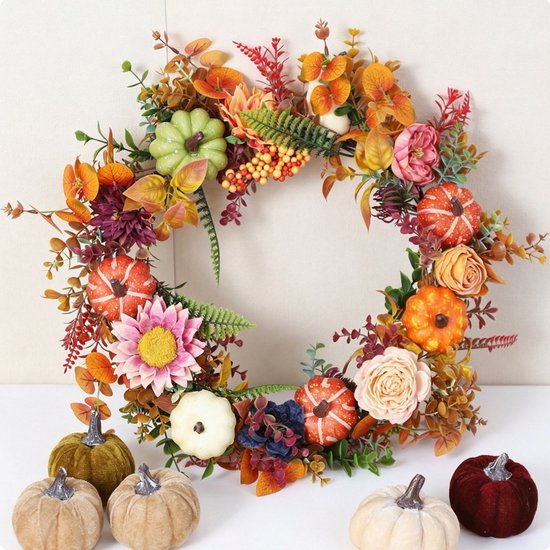 Herfstkrans met diverse pompoenen, bloemen en herfstbladeren in warme tinten. Drie pompoenen op de voorgrond.