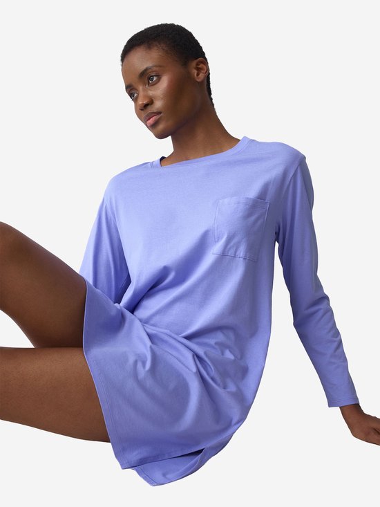 Model zittend in een lavendelkleurig nachthemd met lange mouwen, borstzak en zijsplitten.