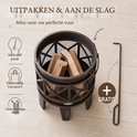 Donkere metalen vuurkorf op pootjes met opgestookt hout, inclusief pook, makkelijk te vervoeren, geen montage nodig.