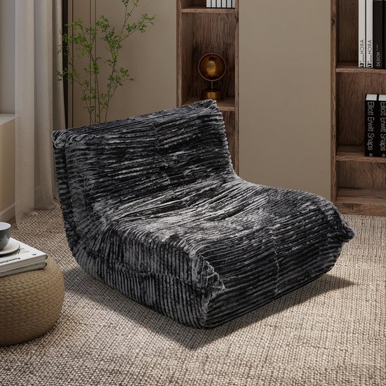 Donkergrijze, geribbelde fluwelen loungefauteuil in een modern woonkamerinterieur.