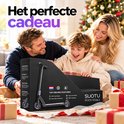 Zwarte Suotu stuntstep in geschenkverpakking met 'Het perfecte cadeau' tekst, bij een gezin met kerstboom.