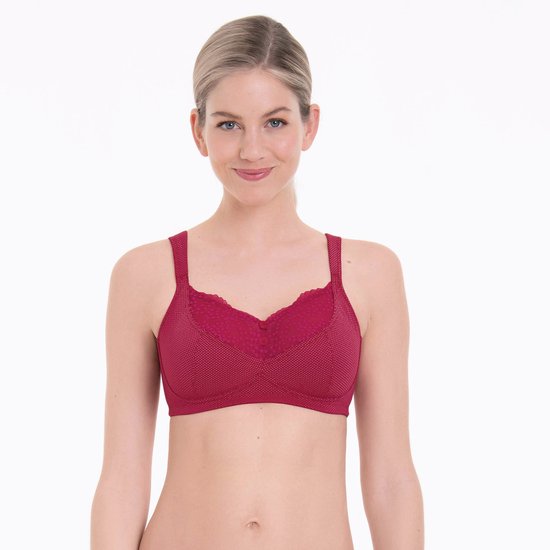 Model draagt een kersenrode Anita Care bh met stippenpatroon en kanten details op de cup.