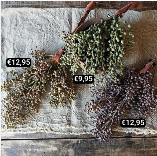 Drie kunstmatige takken met bessen in taupe, groen en bruin op een linnen ondergrond. Prijzen €9,95 en €12,95.