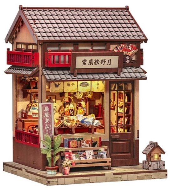 Miniatuur Japanse waaiershop met gedetailleerde gevel, houten dakterras en verlicht interieur met kleine waaiers.