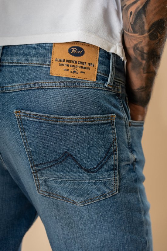 Close-up van het bruine Petrol Industries label op de achterzak met stikseldetails.