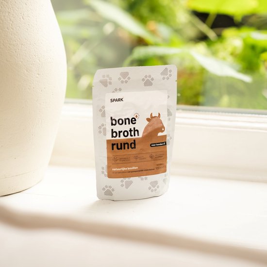 SPARK bone broth rund, 100 ml zakje, met koeienafbeelding en pootafdrukken.