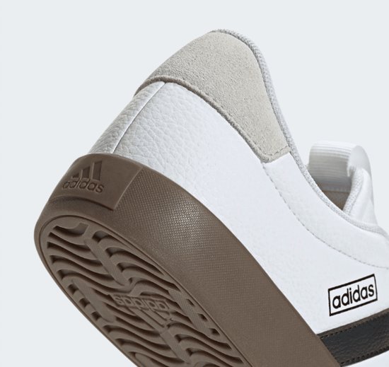 Detail van witte adidas VL Court 3.0 sneaker met een bruine zool, suède hielstuk en adidas-logo op de hiel en zijkant.
