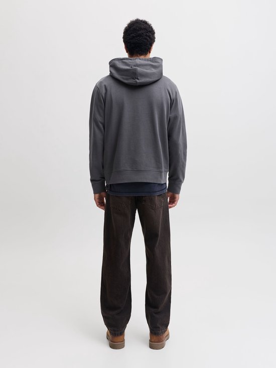 Man in donkergrijze hoodie en bruine broek, achterkant.