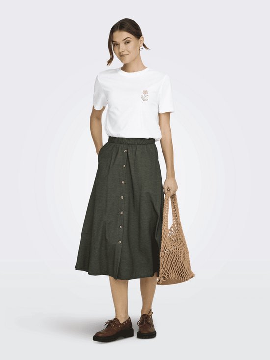 Model in een wit T-shirt met korte mouwen en een kleine gele bloem op de borst, gecombineerd met een donkergroene knooprok.