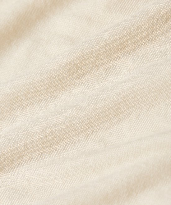 Detailopname van een zachte, beige stof met een fijne gebreide textuur.