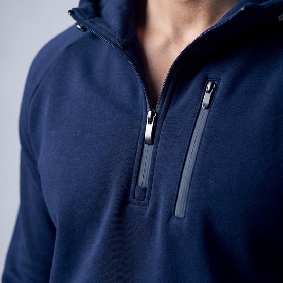 Detailopname van de marineblauwe hoodie met ritssluiting bij de borst.