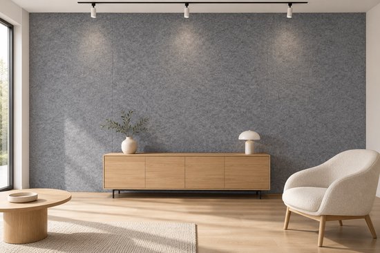 Woonkamer met grijze viltwand, houten dressoir, beige fauteuil en houten vloer.