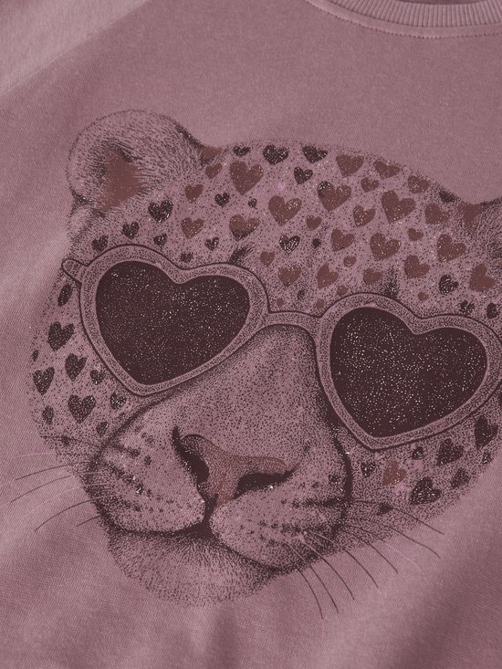 Close-up van een panterprint met hartjes en een luipaard met hartvormige zonnebril op een roze sweater.