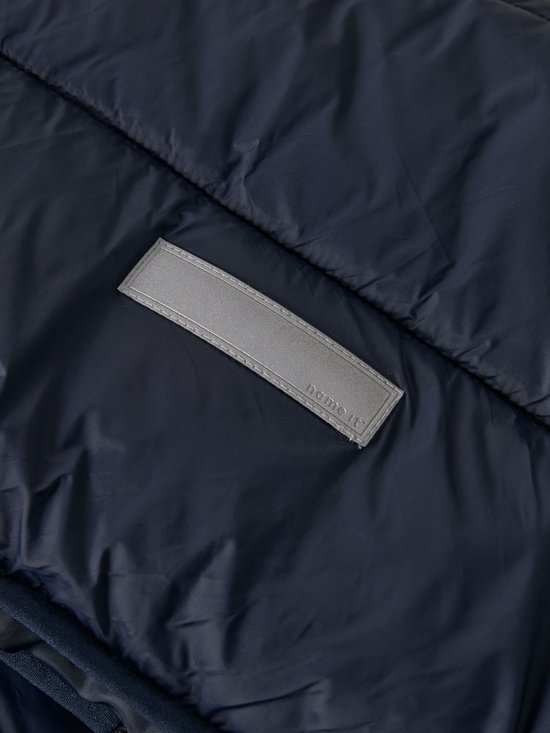 Detail van donkerblauwe, gewatteerde jas met een grijze reflecterende patch met "name it".