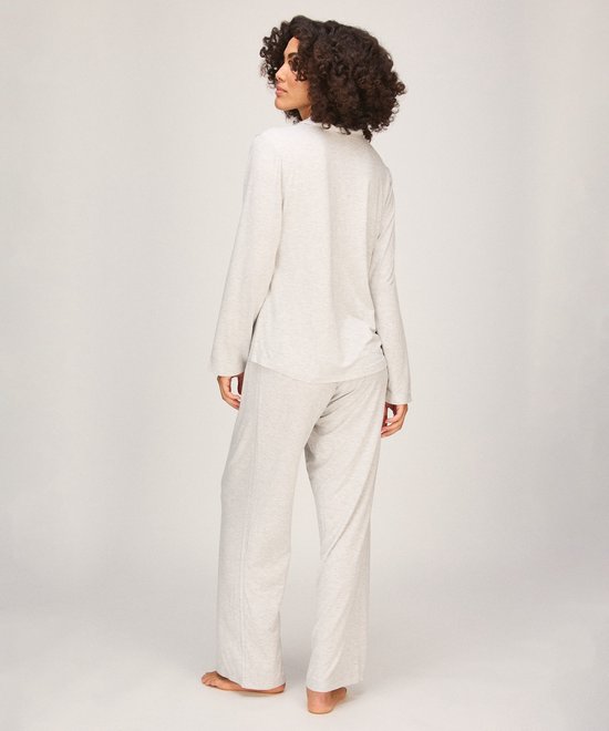 Model van achteren gezien in een lichtgrijze pyjamaset met lange mouwen en een loszittende broek.