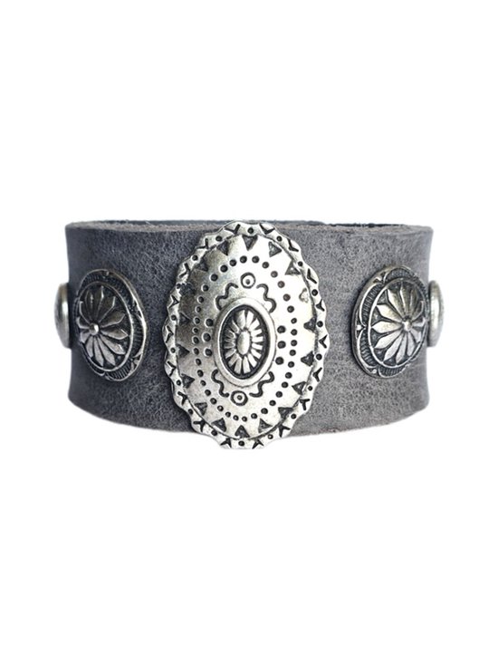 Grijze leren armband met zilverkleurige studs, waarvan een ovale in het midden met bloemenpatroon.