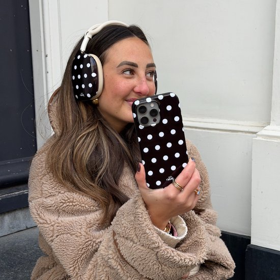 Jonge vrouw met koptelefoon en telefoonhoesje met zwart-wit stippatroon. Koptelefoon met stippen.