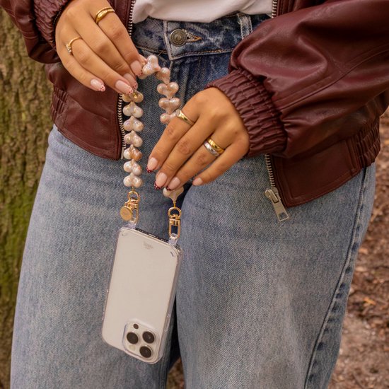 Model draagt een iPhone met een transparant hoesje en een champagnekleurig hartjeskoord van xoxo Wildhearts.