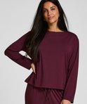 Model draagt een paarse pyjamatop met lange mouwen en een bijpassende broek.