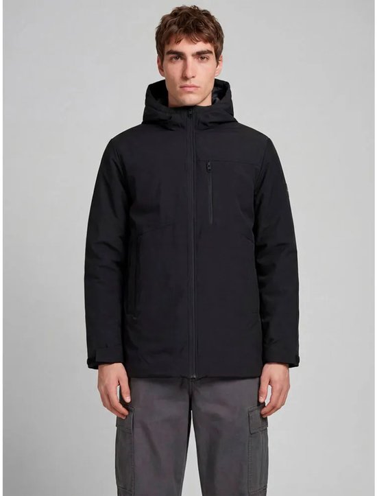 Model draagt een zwarte JJREBEL Toronto parka met capuchon en ritsvak op de borst, gecombineerd met grijze cargobroek.