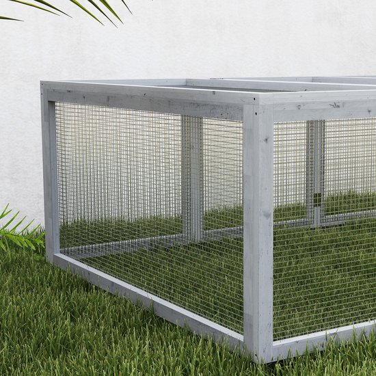 Een grijs houten konijnenhok van gaas, geplaatst op groen gras.