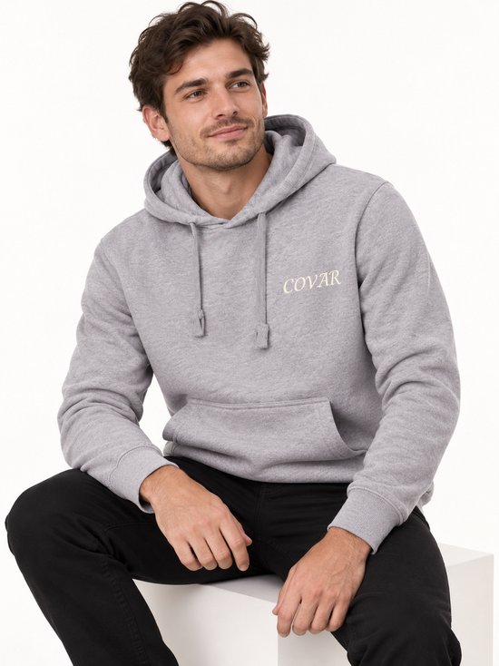 Man met grijze hoodie met 'COVAR' print op linkerborst.