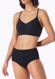 Model draagt een zwarte bustier met V-hals, gecombineerd met hoge bikinislip.