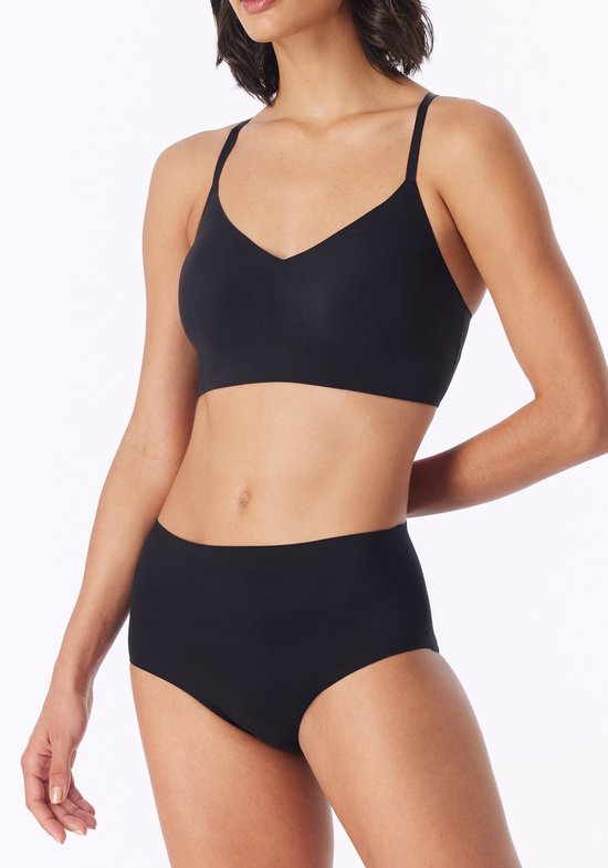 Model draagt een zwarte bustier met V-hals, gecombineerd met hoge bikinislip.