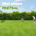Meisjes spelen hockey in een tuin met een zwart EXIT voetbaldoel op het gras. Tekst: Niet alleen voetbal.