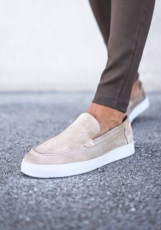 Beige suède loafers aan de voeten gecombineerd met een bruine broek.