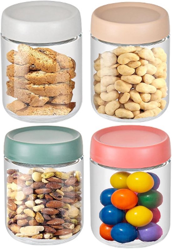 Vier glazen voorraadpotten met deksels in wit, beige, groen en roze, gevuld met verschillende snacks.