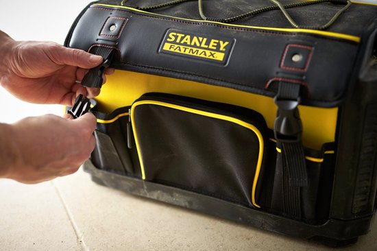 Handen sluiten de gespen van een zwarte en gele STANLEY FatMax gereedschapstas.