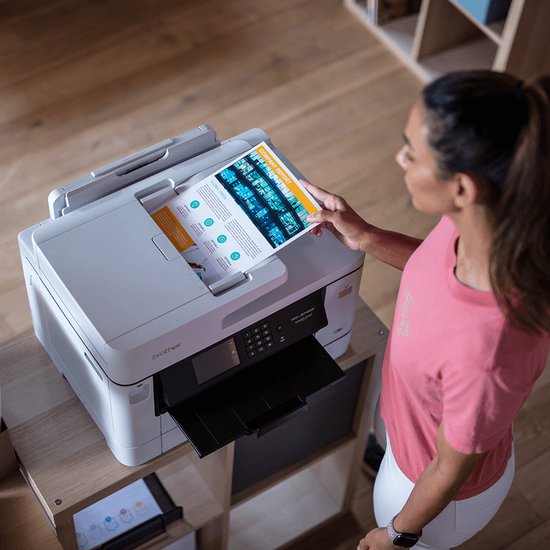 Vrouw met een roze shirt die een document in de Brother printer legt.