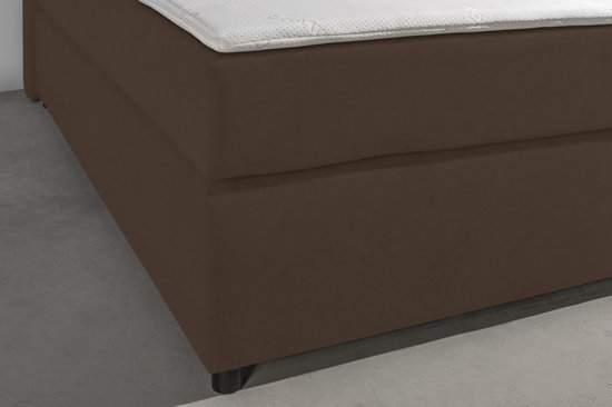 Detail van de taupe boxspringbank met een wit gestoffeerd matras.