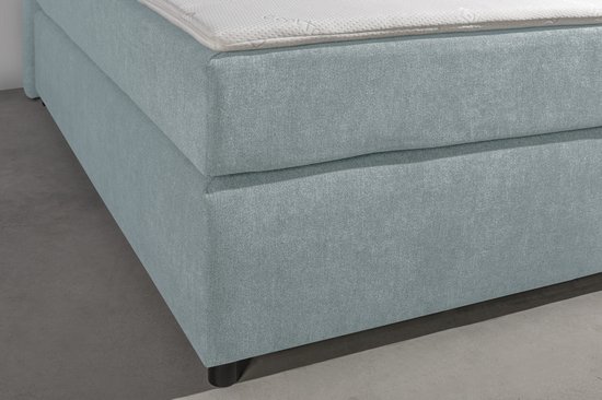 Detailopname van de textuur van de lichtblauwe stoffering van een boxspring.