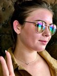 Jonge vrouw met zonnebril en een regenboog gekleurd oordopje in haar rechteroor.