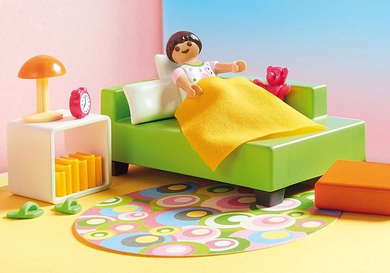Kind op groen bankje met gele deken en roze beer, in speelgoedkamer met rond vloerkleed.