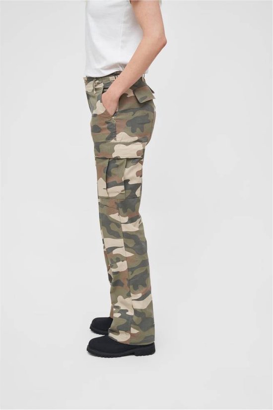 Vrouw met camouflage cargo broek en witte t-shirt, van de zijkant gezien.