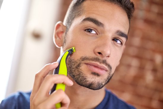 Homme barbu se taille le visage avec le Philips OneBlade vert et noir.