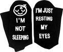 Zwarte sokken, op de ene staat 'I'M JUST RESTING MY EYES', op de andere 'I'M NOT SLEEPING' met een slapende smiley.