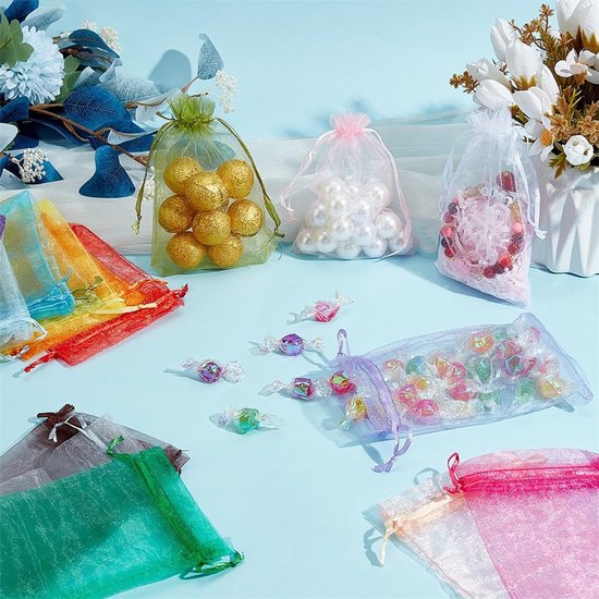 Diverse organza zakjes in verschillende kleuren, gevuld met ballen, parels en snoepjes.