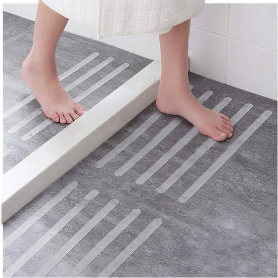 Voeten op grijze tegelvloer in douche; antislip strips aangebracht.