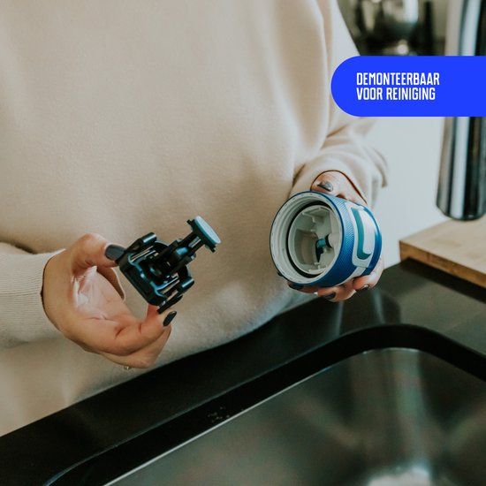Handen tonen hoe de delen van het deksel van een blauwe Kambukka drinkfles uit elkaar gehaald kunnen worden. Tekst 'Demonteerbaar voor reiniging'.
