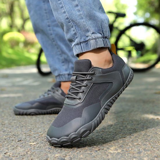 Personne marchant dehors avec des chaussures minimalistes grises, vélo en arrière-plan.