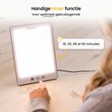 Vrouw met vinger op timerknop van een witte daglichtlamp met bruin frame. Instelbaar op 15, 30, 45 of 60 minuten.