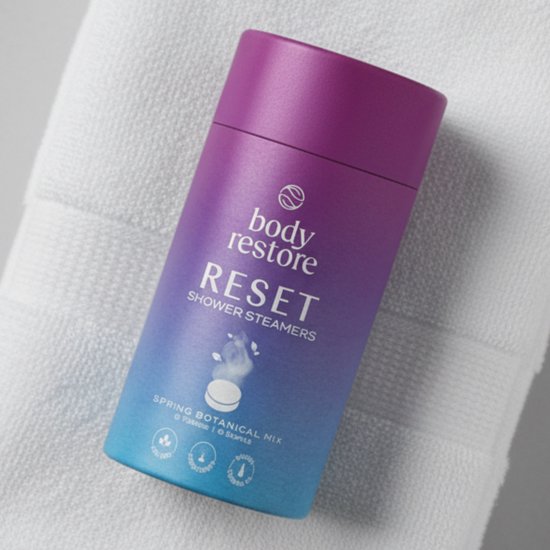 Body Restore RESET Shower Steamers in paars-blauwe cilinder op een witte handdoek.