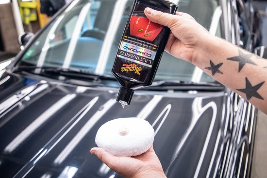 Fles Meguiar's Ultimate Compound met gele en zwarte etikettering. Toont een rode auto met "Voor" en "Na" secties.