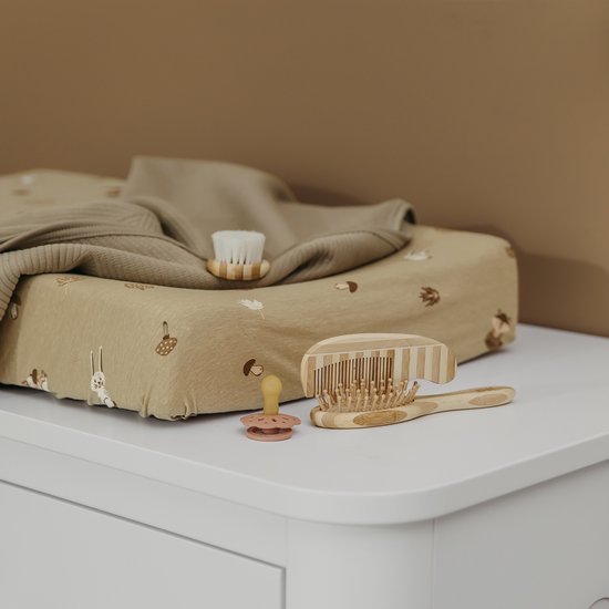 Zandkleurige aankleedkussenhoes met bosdierenprint, met kleding en babysetting.