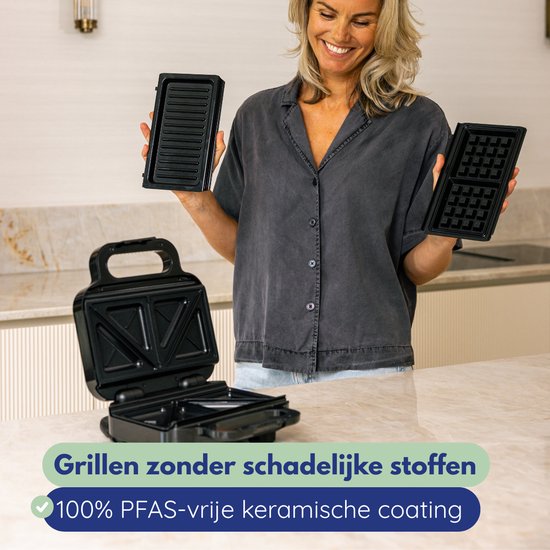 Vrouw houdt grill- en wafelplaten vast van een zwart apparaat. Grillen zonder schadelijke stoffen.