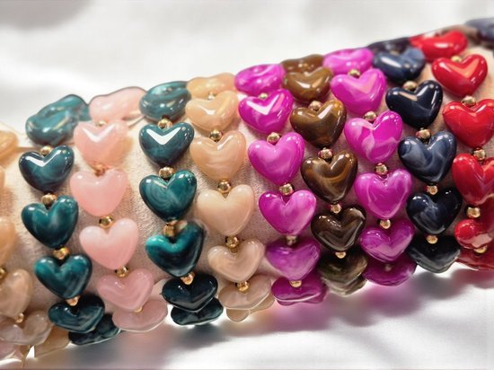 Meerdere rijen armbanden met hartvormige kralen in diverse kleuren, waaronder roze, blauw en rood.